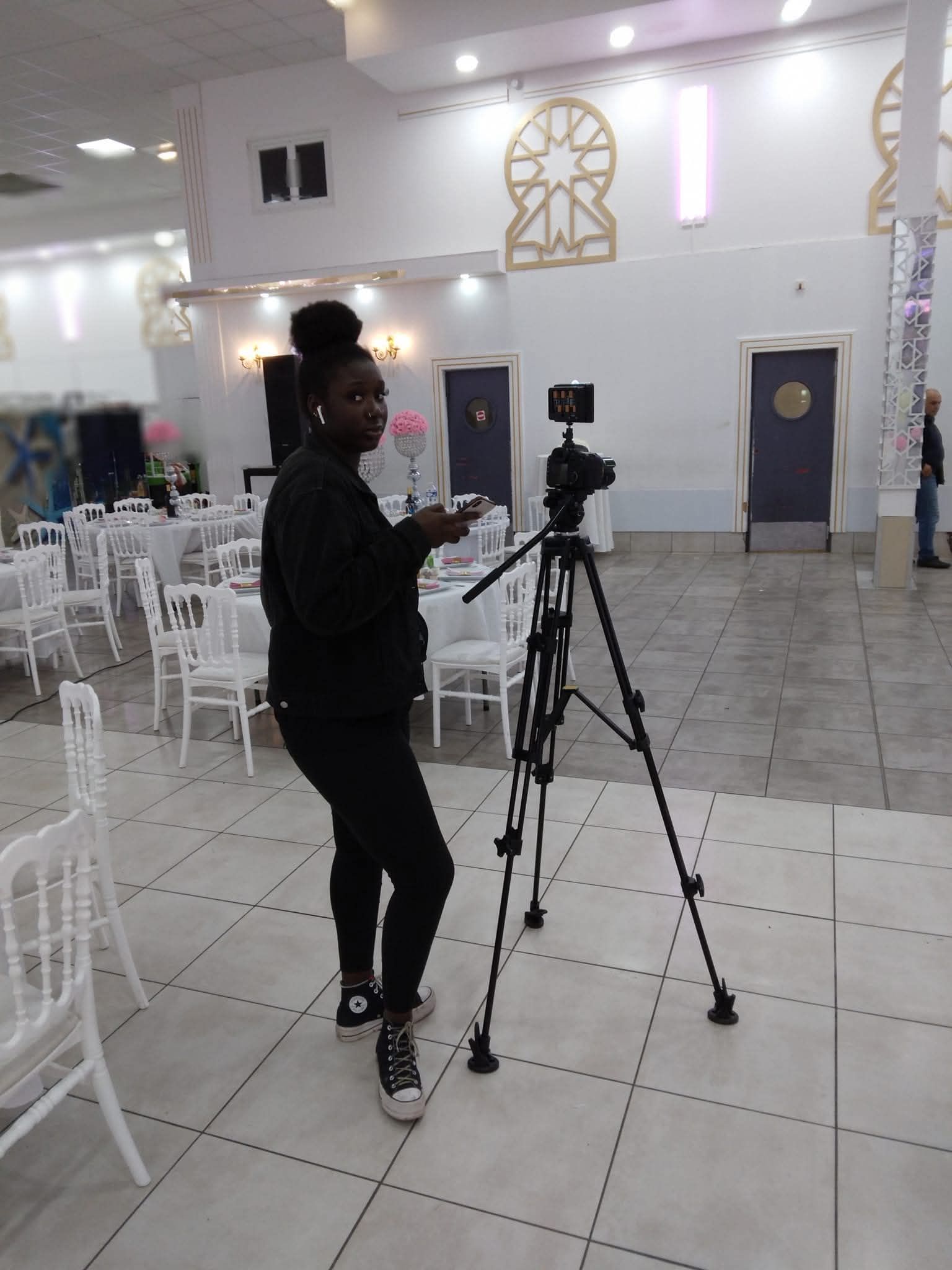 Des bénévoles distribuent des vêtements à une personne, probablement dans un centre de collecte. Cette personne porte une cape verte.