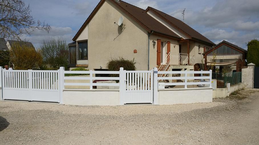 Portail avec clôture blanche devant une maison