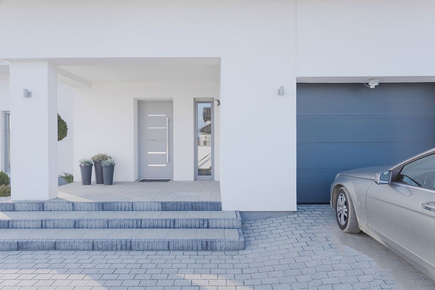 Porte d'entrée grise sur une maison neuve avec garage