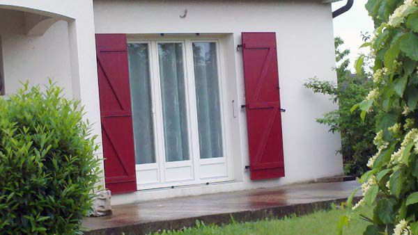 Volets rouges sur une porte-fenêtre