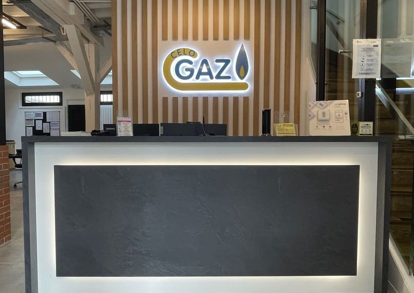 Bureau d'accueil avec un logo CELO GAZ rétroéclairé sur un mur à lattes de bois dans un bureau moderne.