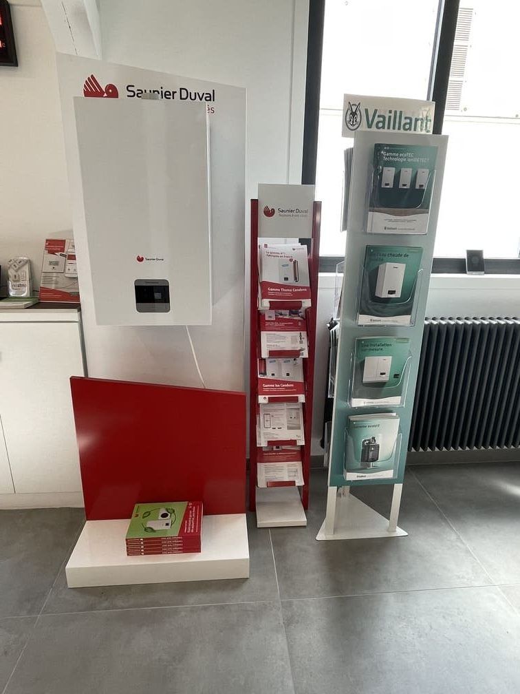 Une présentation en showroom mettant en vedette une chaudière murale Saunier Duval et deux présentoirs verticaux avec des brochures pour Saunier Duval et Vaillant.