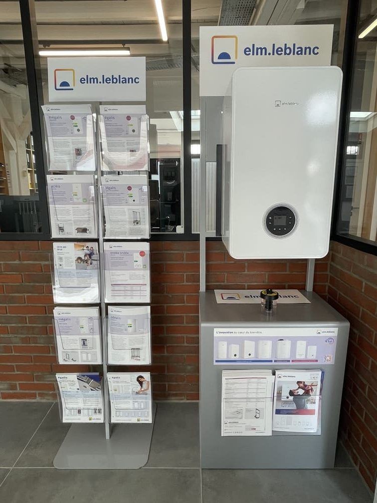 Présentation en showroom des chaudières elm.leblanc, avec un modèle mural et un présentoir à brochures contre un mur de briques.