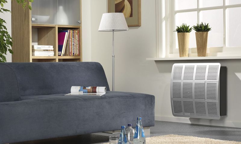 Un salon moderne avec un canapé bleu, un lampadaire, une étagère en bois et un radiateur métallique sous une fenêtre.