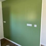 Mur peint en vert avec garniture blanche et prises électriques.