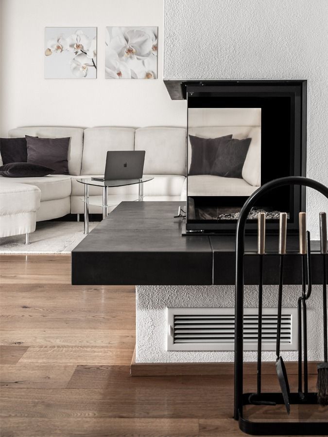Modernes Wohnzimmer mit Kamin, weißem Sofa, Laptop und Holzboden.