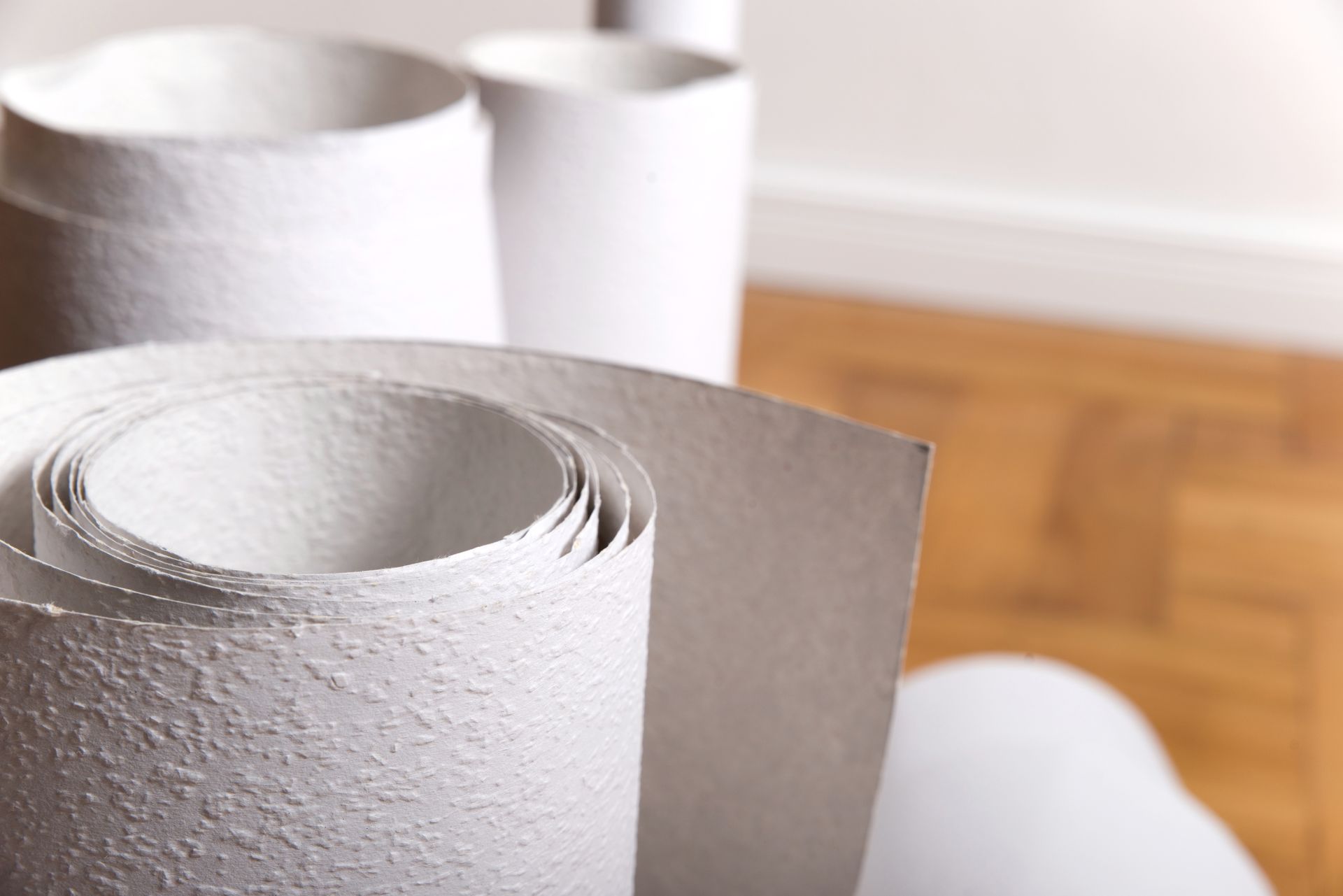 Rollen aus strukturiertem, weißem Papier auf Holzboden.