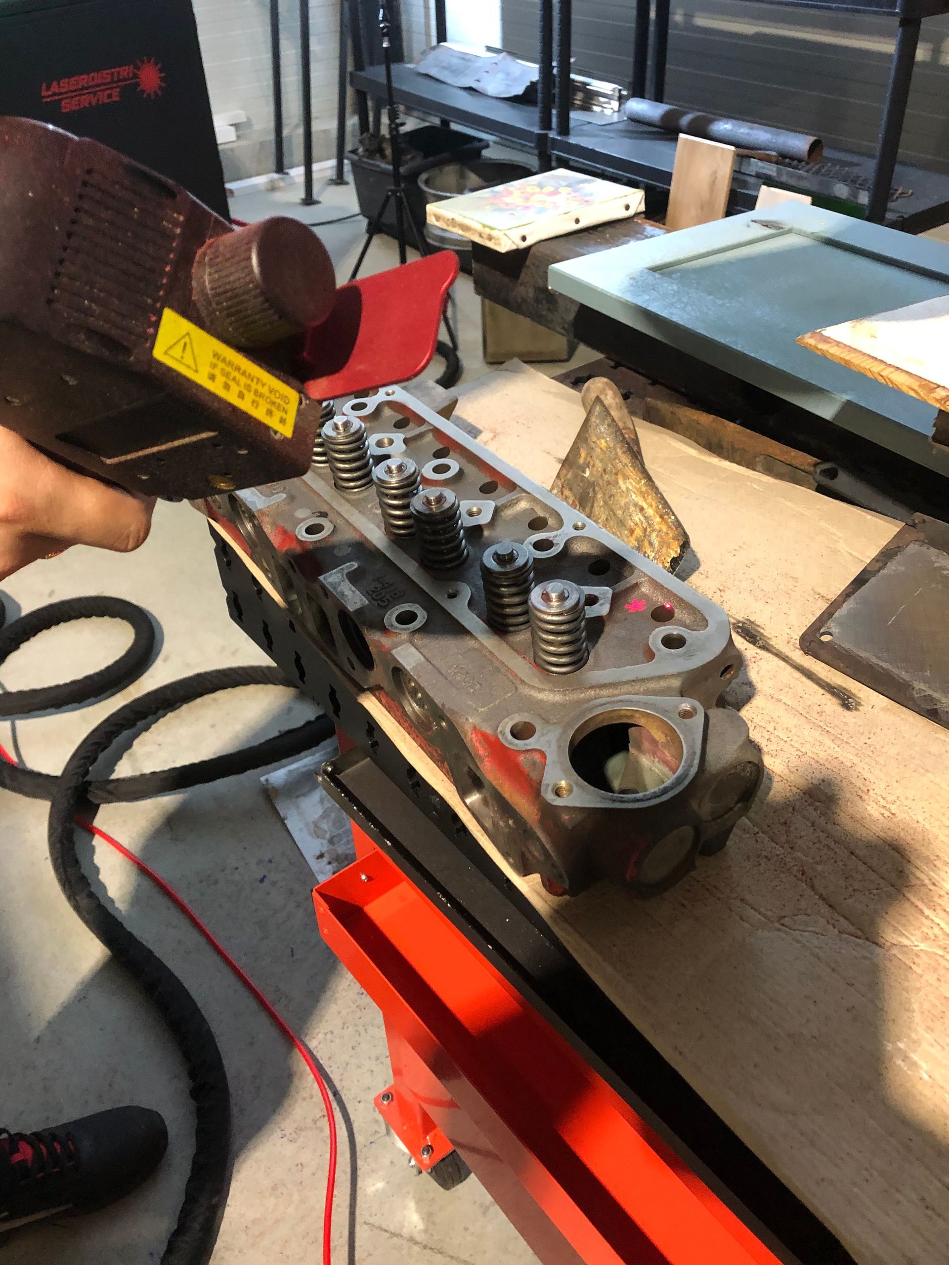 Une personne utilise un laser sur une culasse de moteur.