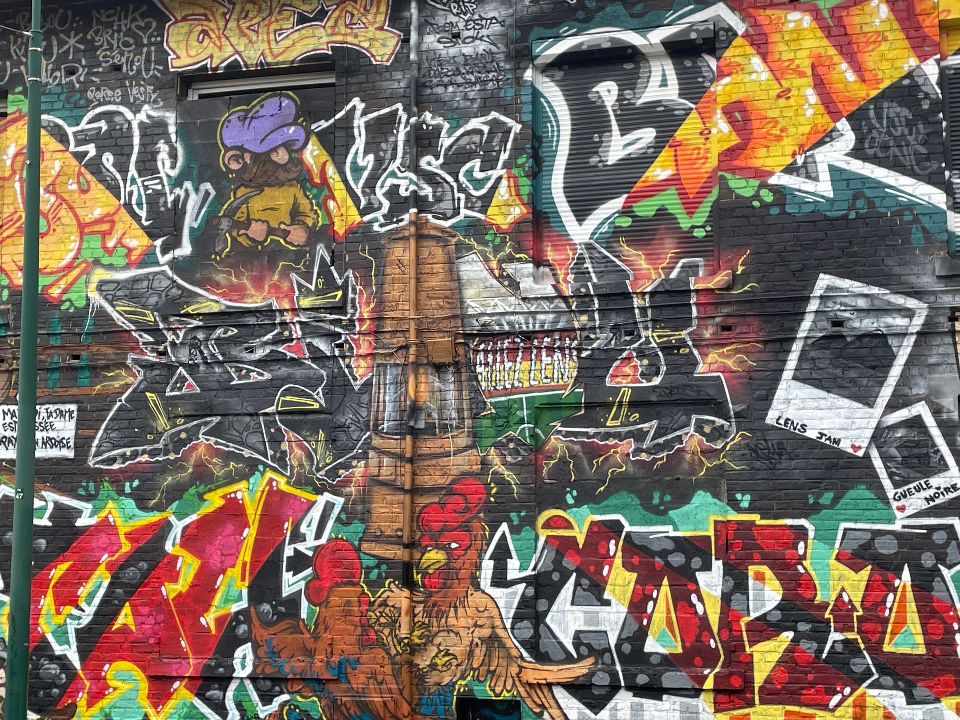 Art graffiti coloré sur un mur de briques, présentant des formes abstraites.