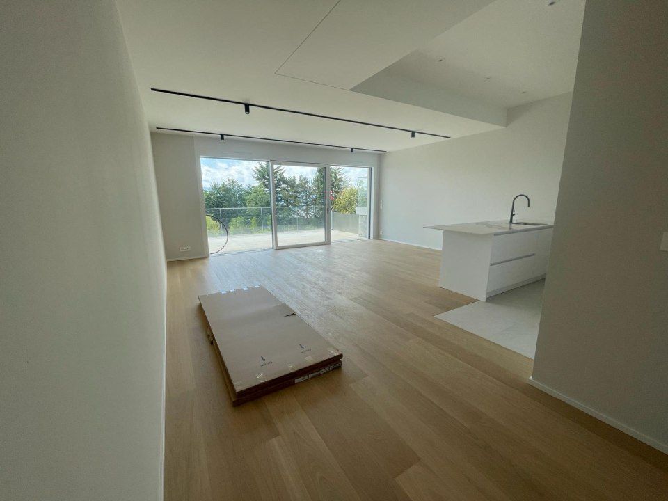 Un salon vide avec parquet et portes coulissantes en verre.