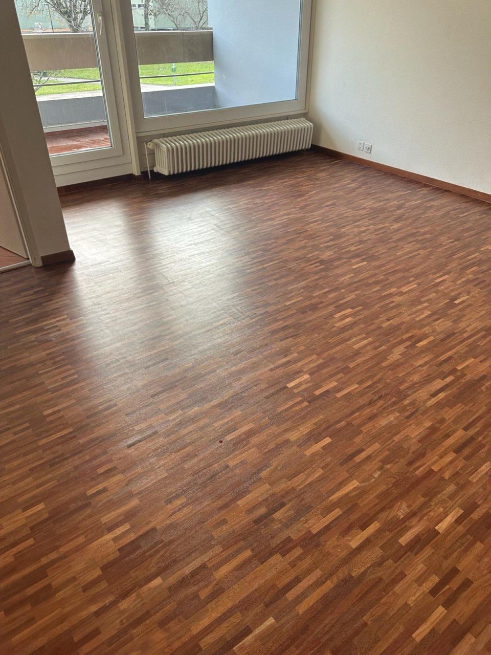 Un salon avec un plancher en bois et une fenêtre.