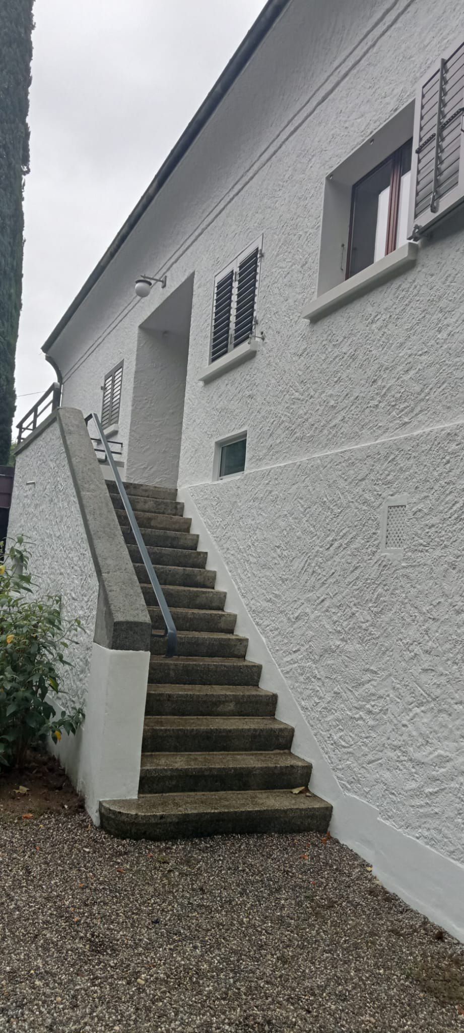 Une maison blanche avec des escaliers menant à la porte d'entrée.