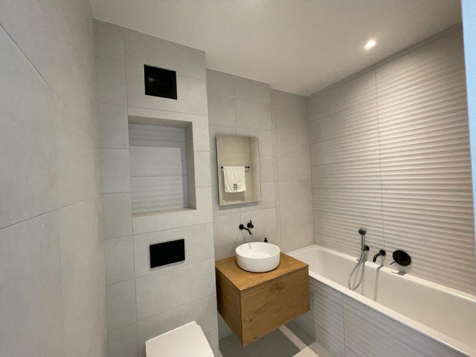 Une salle de bain avec lavabo, WC, baignoire et miroir.