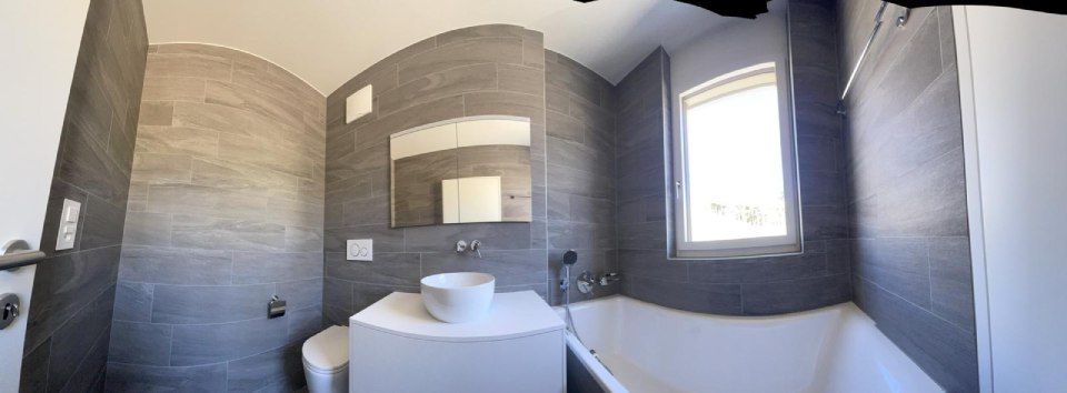 Une salle de bain avec baignoire, lavabo, WC et fenêtre.