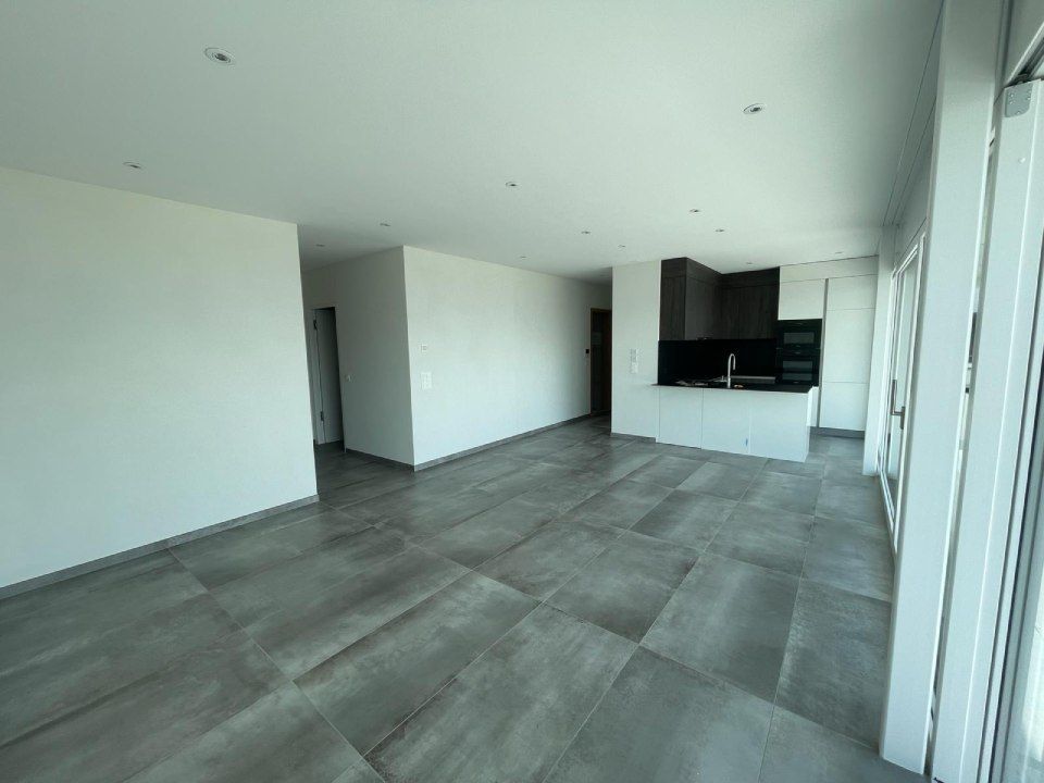 Un salon vide avec une cuisine en arrière-plan.