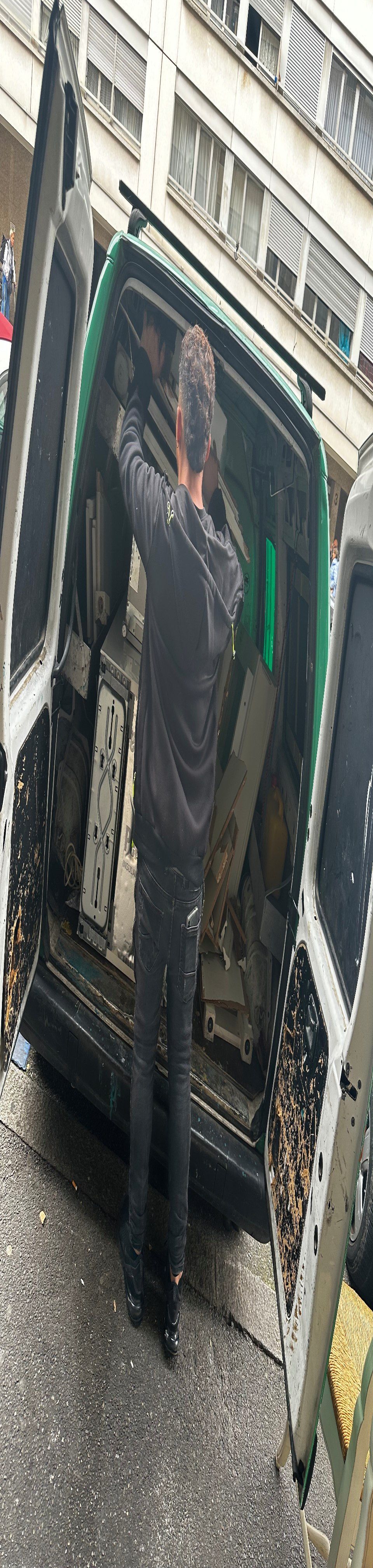 Un homme se tient devant une camionnette verte.