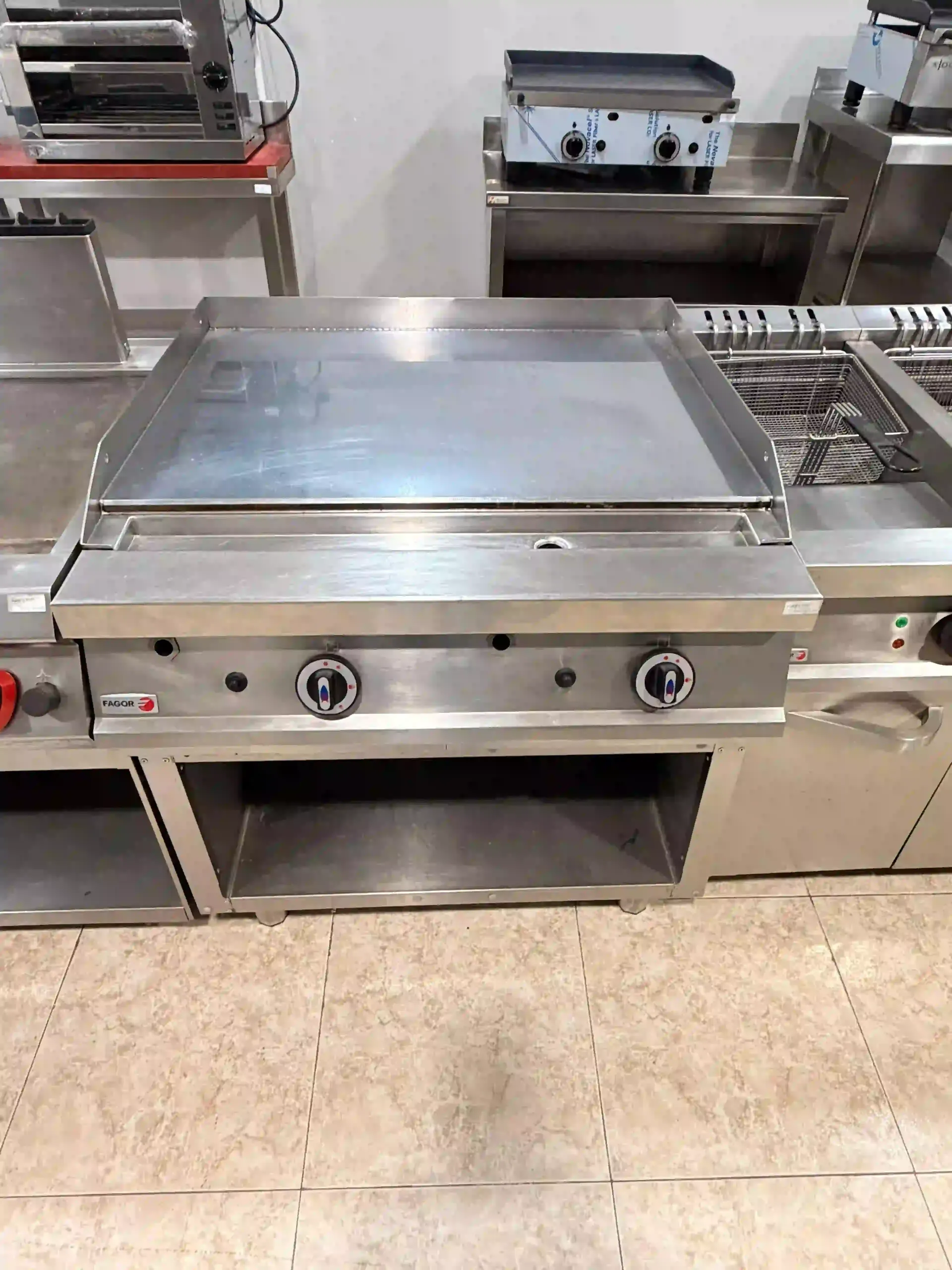 Plancha comercial de acero inoxidable con superficie plana y perillas frontales