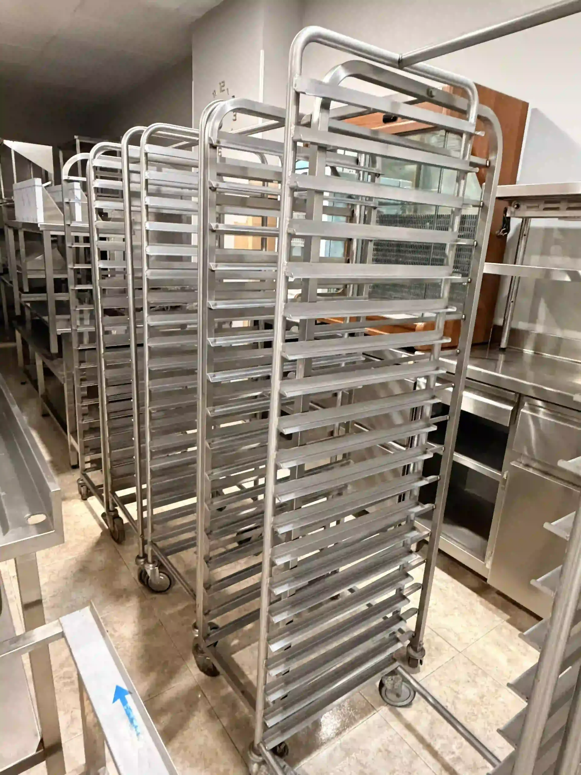 Estanterías metálicas altas para panadería con bandejas vacías en una cocina comercial.