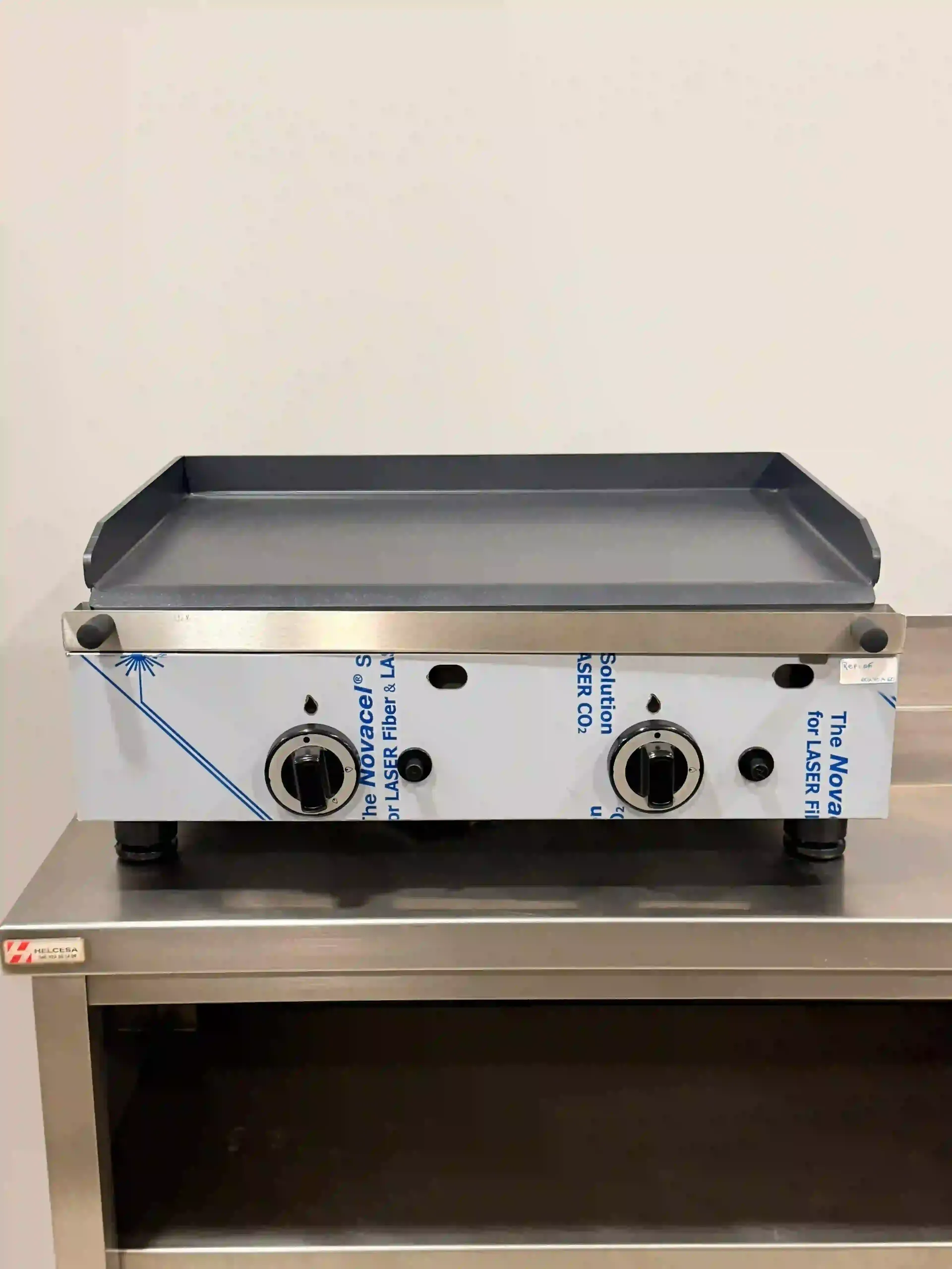 Plancha de encimera de acero inoxidable con dos perillas de control sobre un soporte de metal.