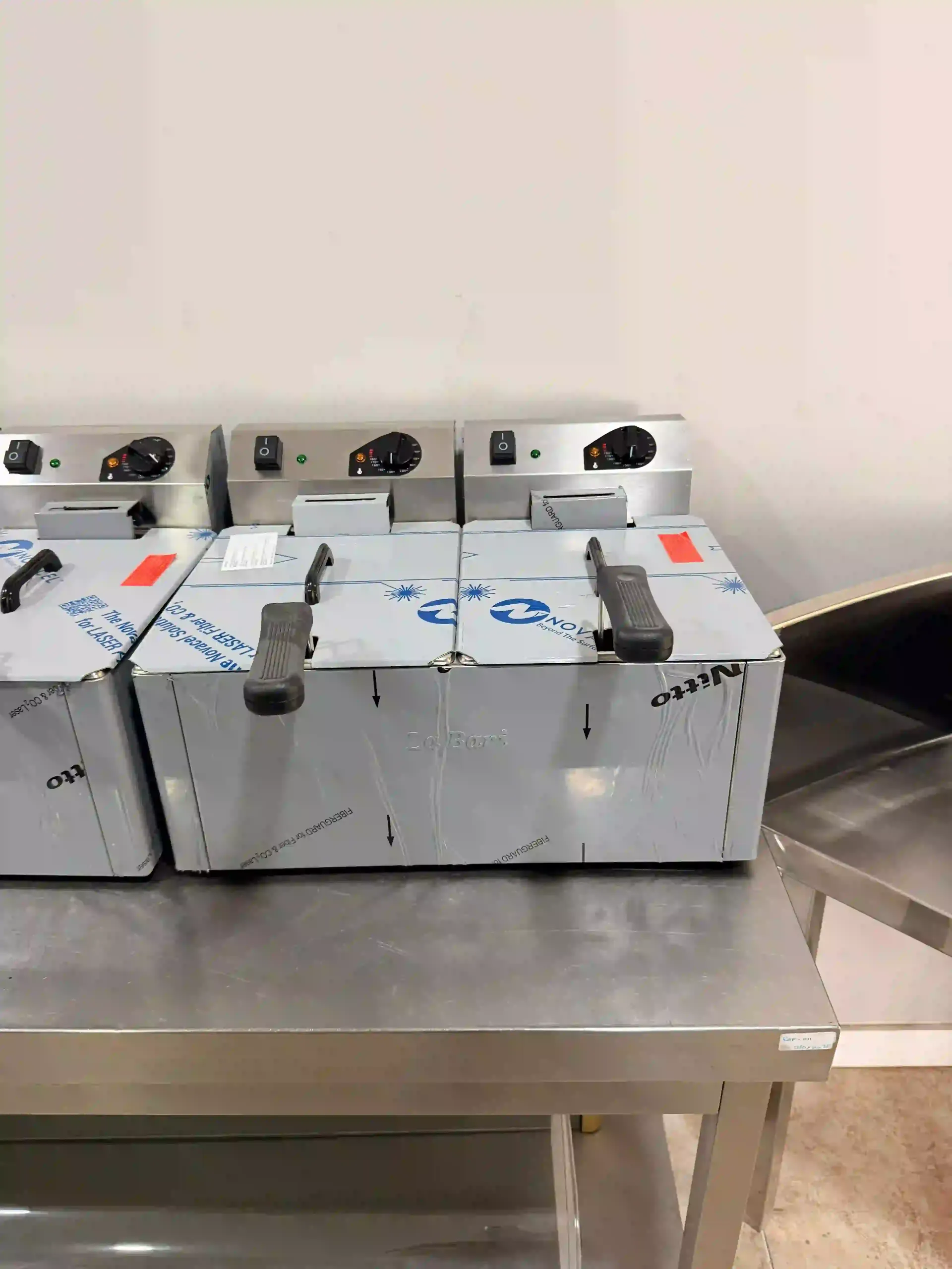 Tres paquetes de baterías grises con asas negras sobre una mesa de metal en un laboratorio o taller.