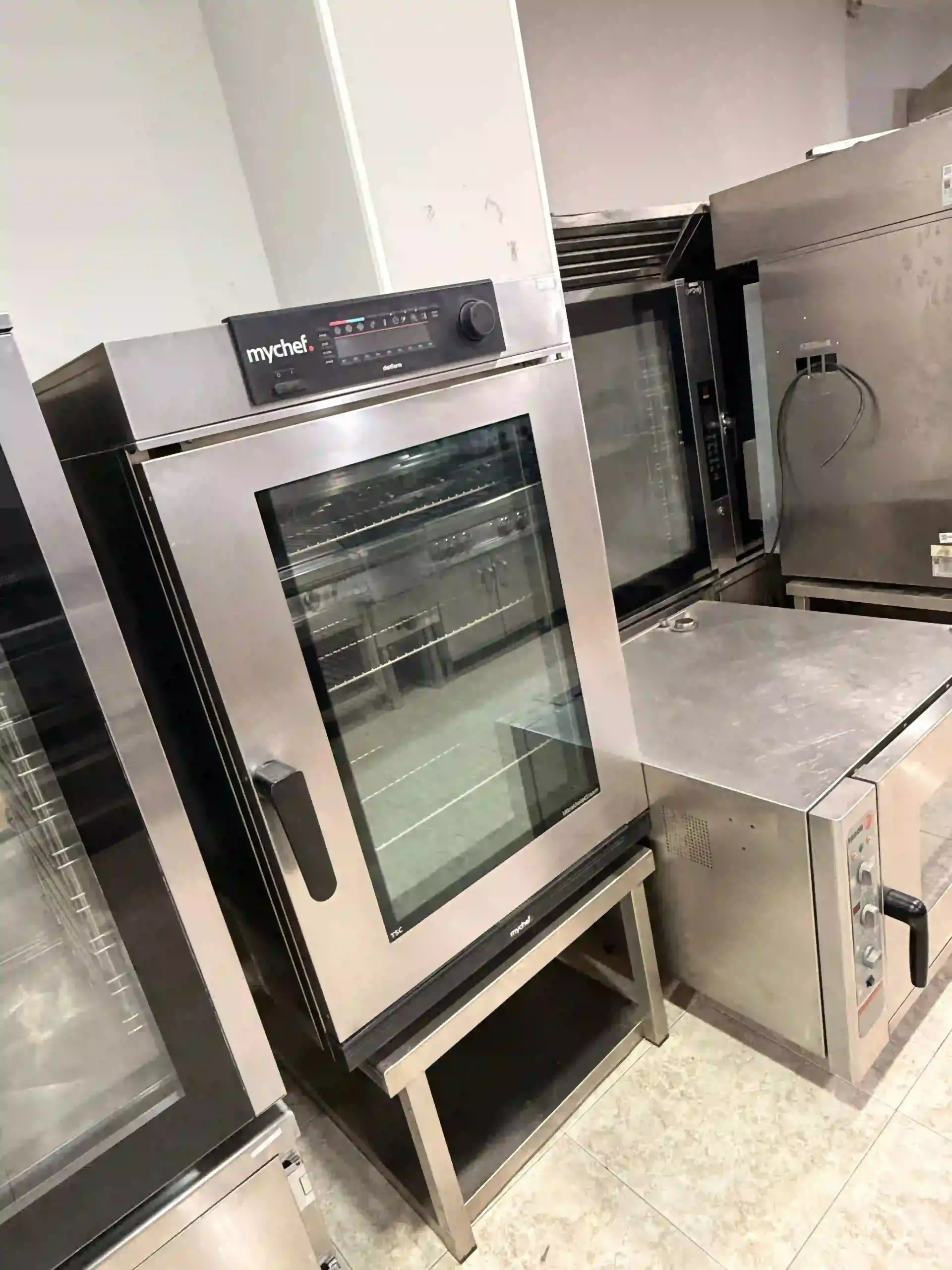 Hornos comerciales de acero inoxidable y hornos en el suelo de una cocina, vistos desde un ángulo.