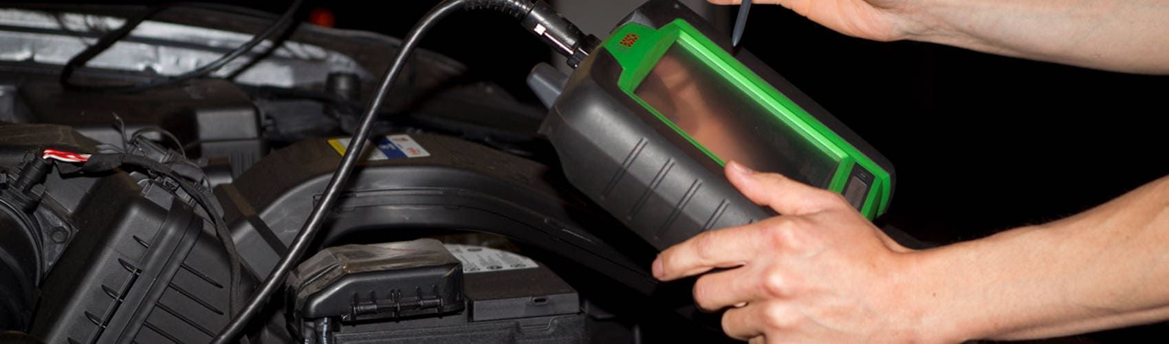 Eine Person arbeitet an einem Auto mit einem grün-schwarzen Diagnosegerät