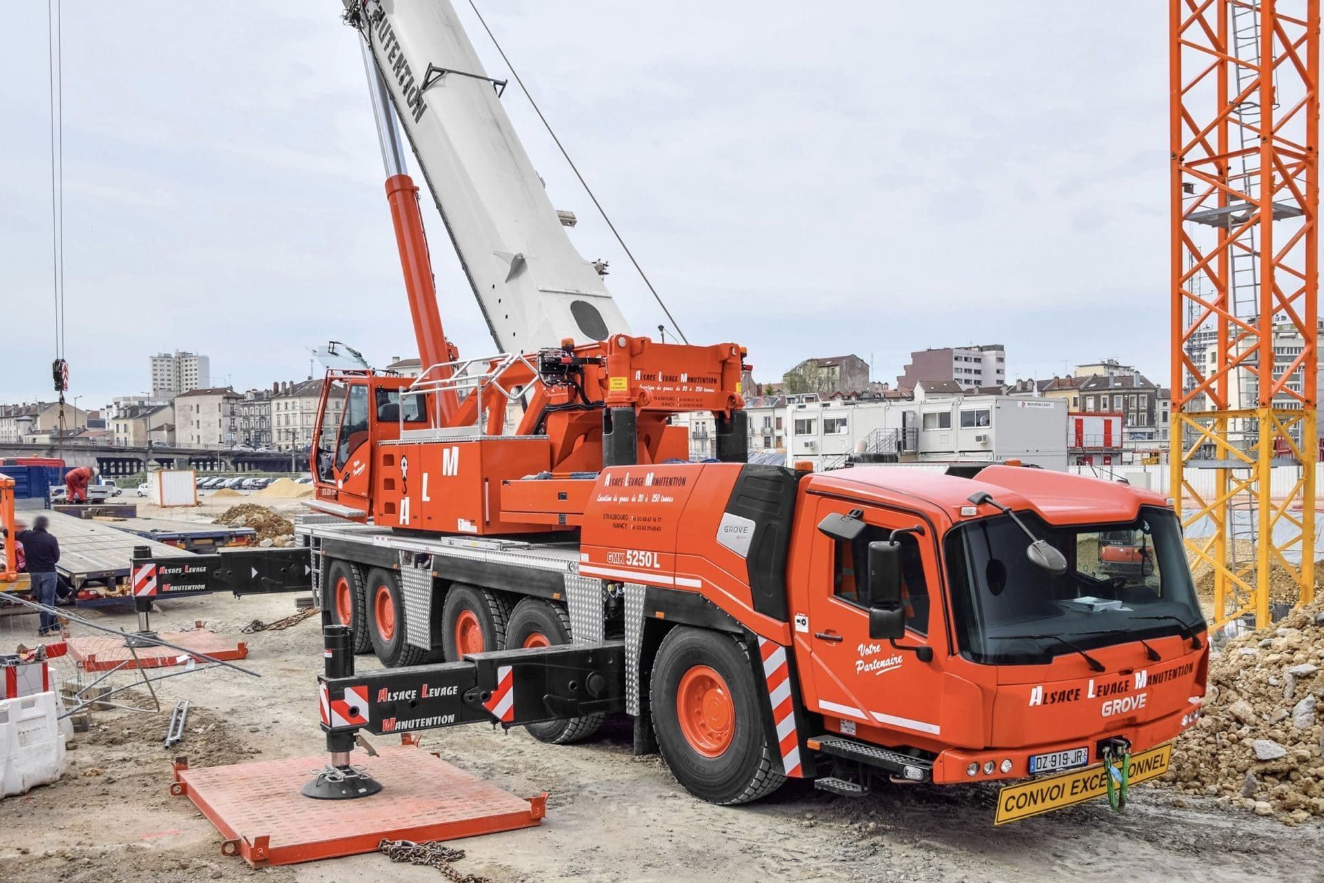 camion-grue rouge avec sa grue déployée sur un chantier