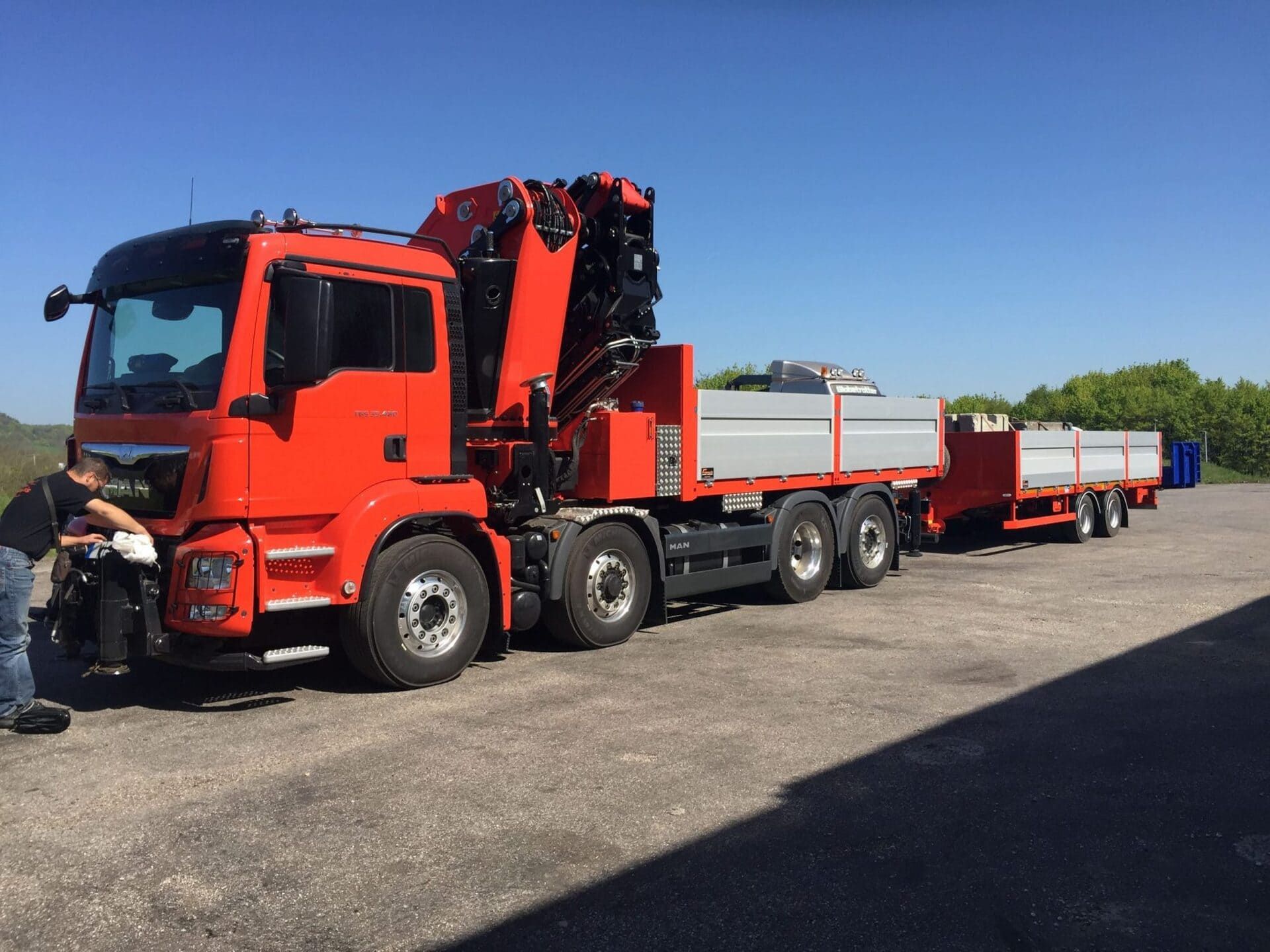 Camion-grue rouge et gris garé sur un parking