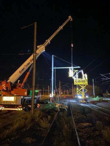 Camion grue accompagné d'une nacelle intervenant sur les rails durant la nuit