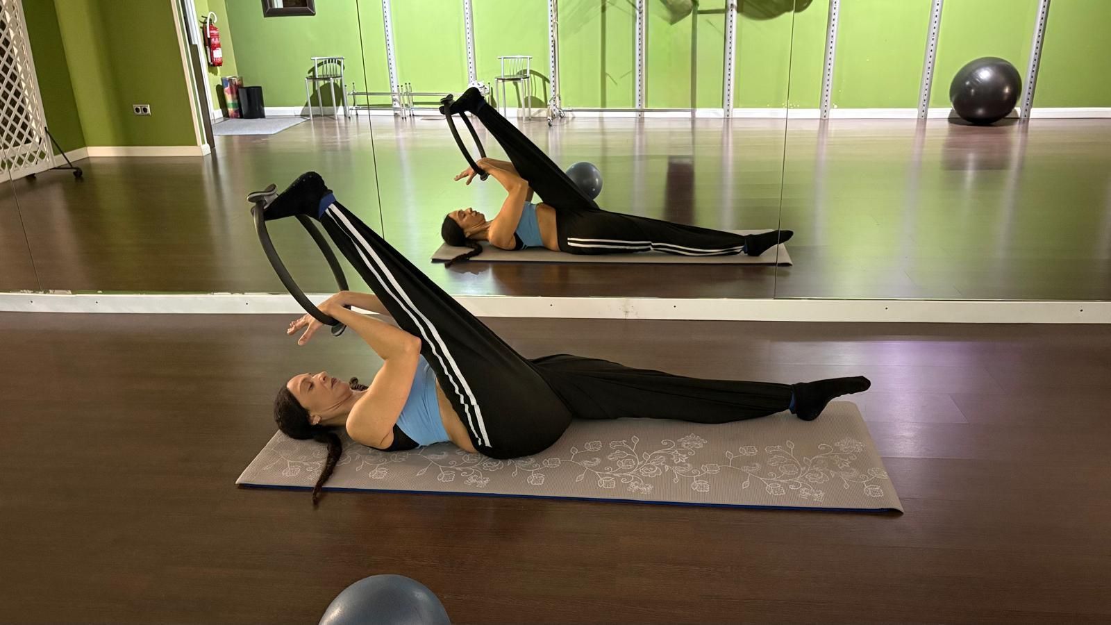 Persona haciendo ejercicio con una pelota de ejercicio morada sobre una colchoneta en un gimnasio.