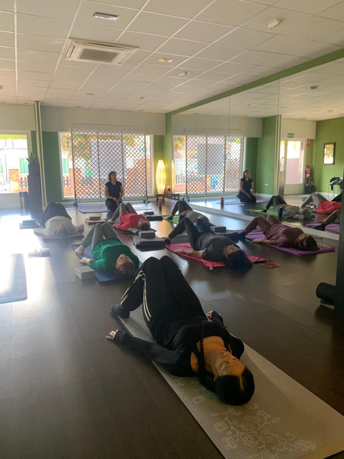 Mujer vestida de negro para hacer ejercicio haciendo ejercicios abdominales con una pelota