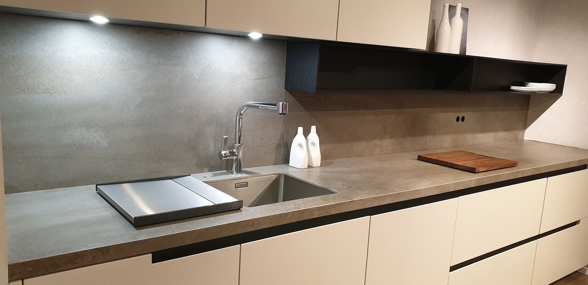 Cocina moderna con encimeras claras, fregadero de acero inoxidable e iluminación debajo de los gabinetes.