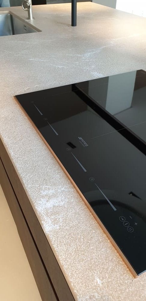 Placa de cocina de vidrio negro integrada en una encimera de color claro en una cocina moderna.