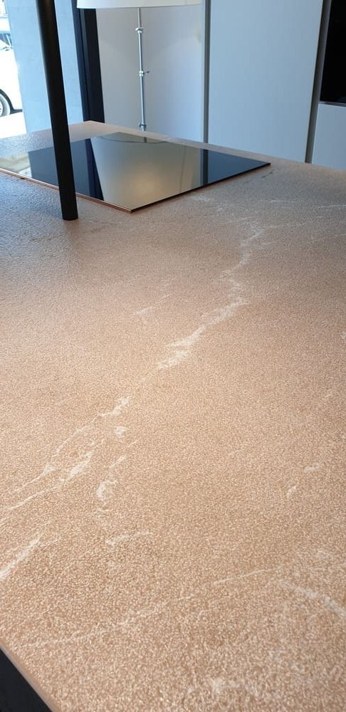 Una encimera con una estufa negra, un poste negro y una veta blanca.