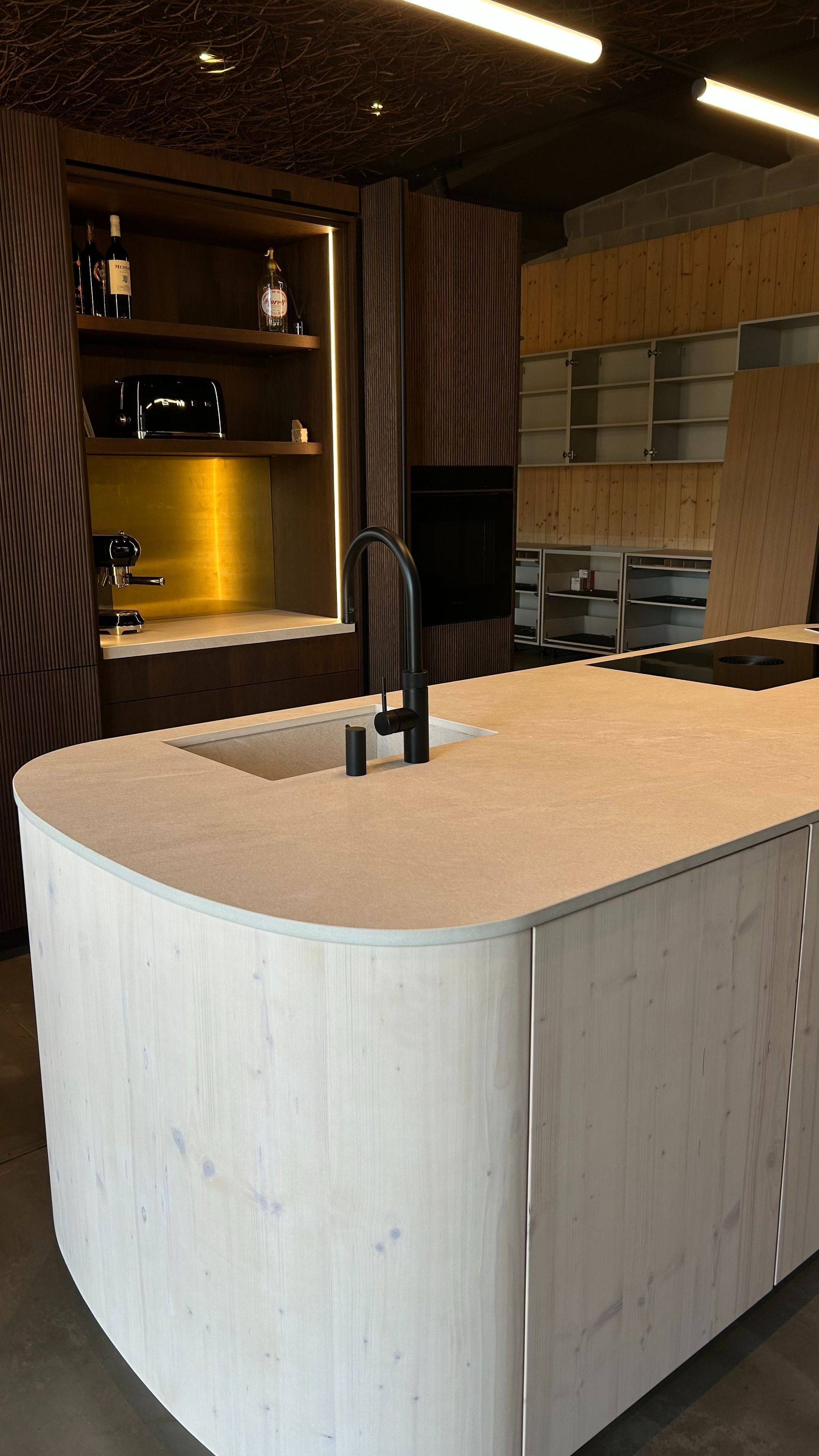 Cocina moderna con isla de color claro, grifo oscuro y gabinetes de madera oscura.