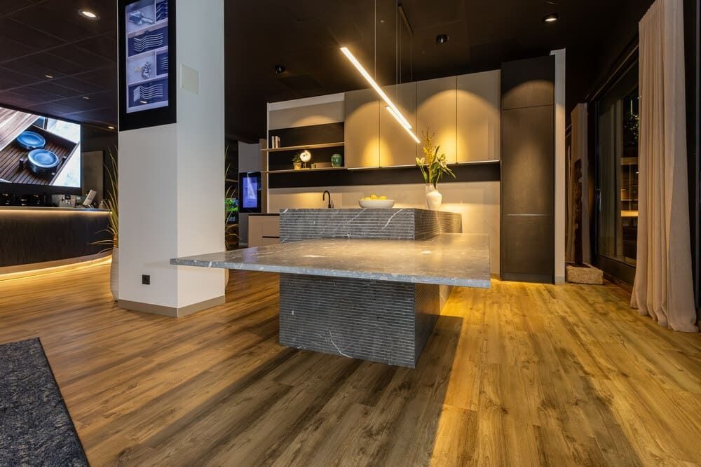 Cocina moderna con isla de mármol y suelos de madera clara.