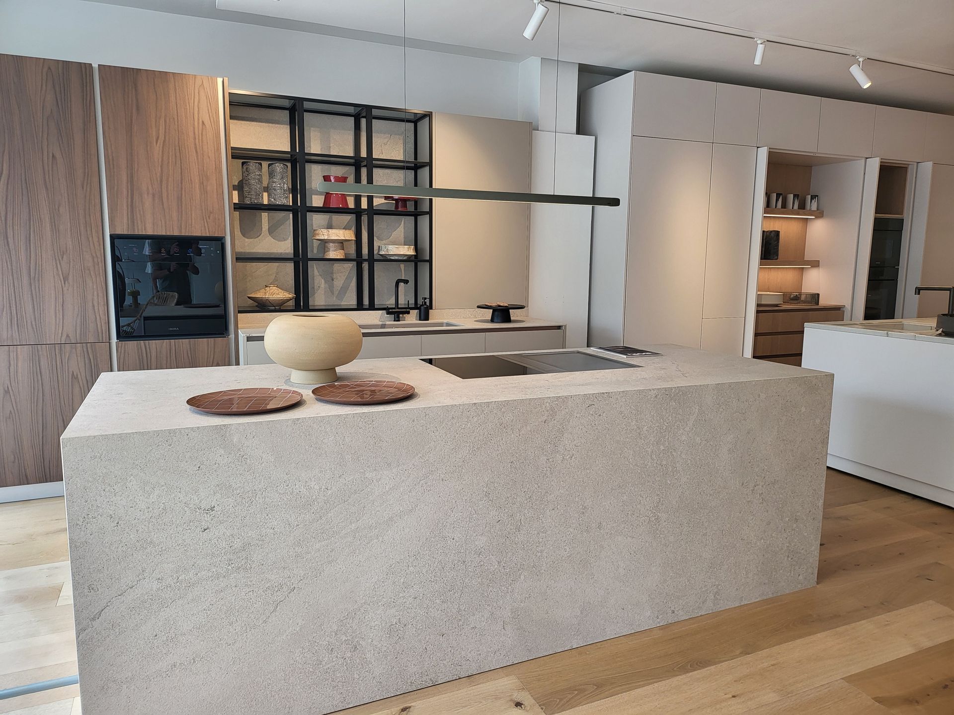 Cocina moderna con isla de piedra clara, gabinetes de madera y detalles en negro.