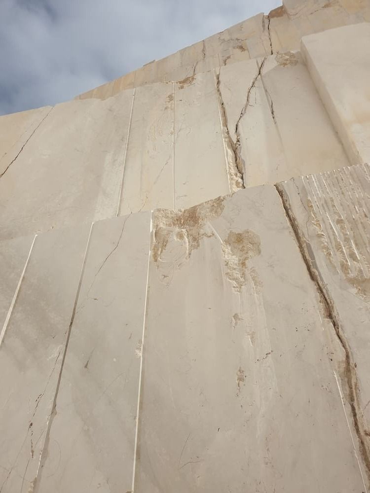 Cantera de mármol blanco, que muestra grandes bloques cortados con grietas, contra un cielo nublado.