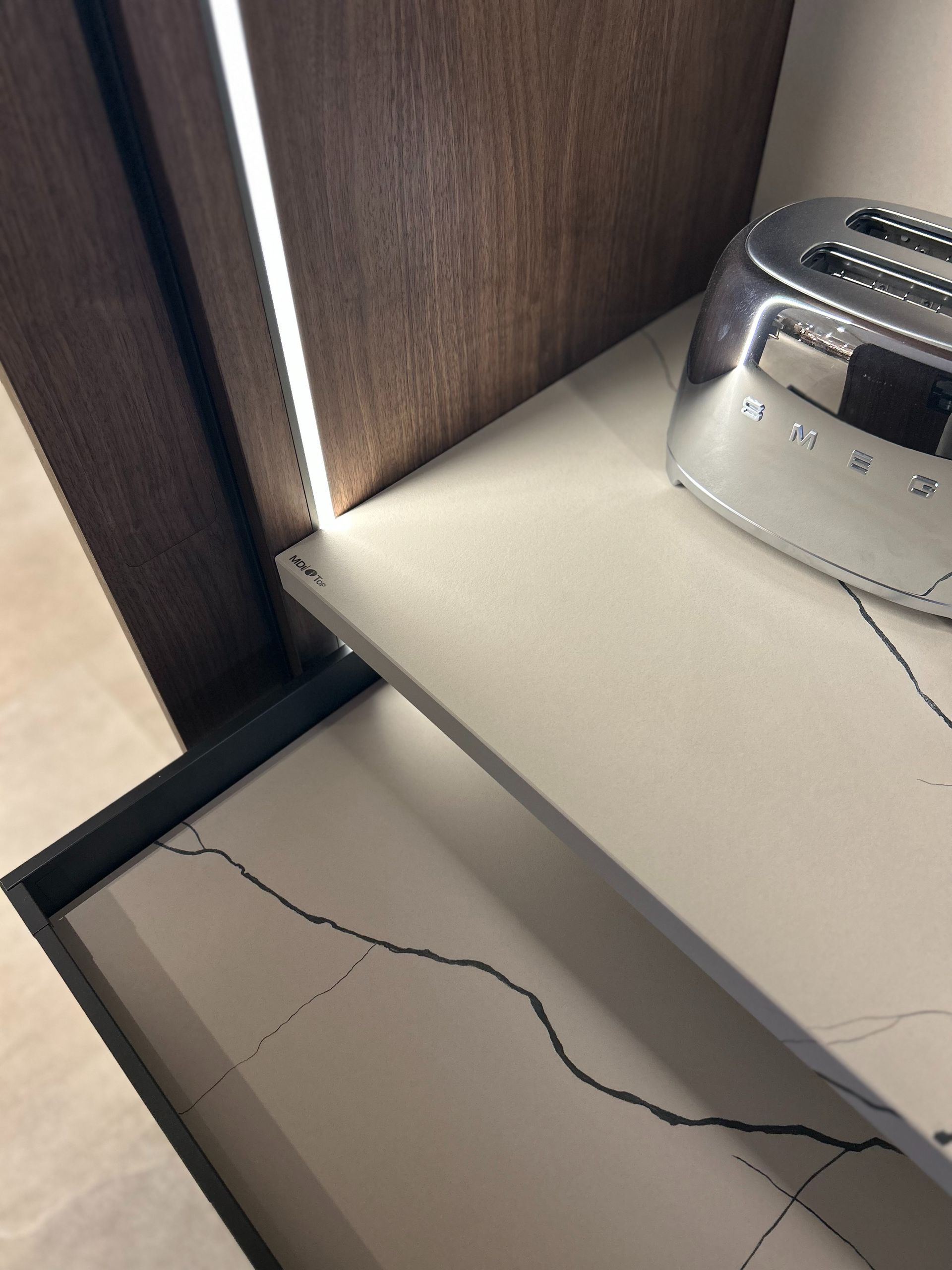 Primer plano de una encimera de cocina moderna con una tostadora cromada. Cajón abierto.