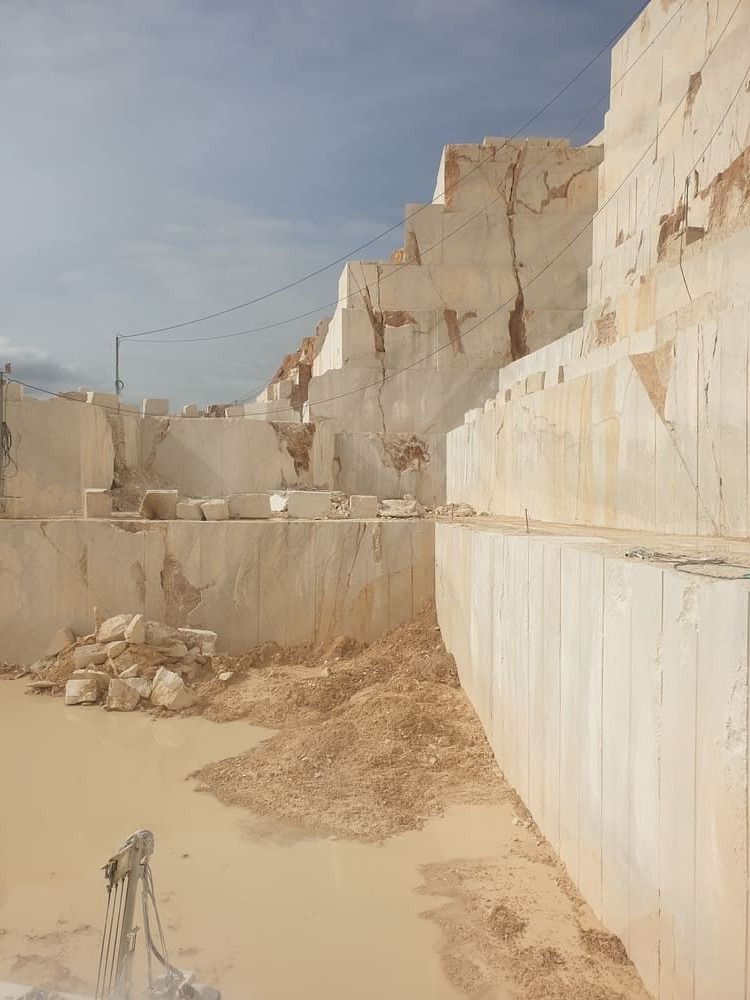 Cantera con grandes muros escalonados de piedra blanca y agua fangosa.
