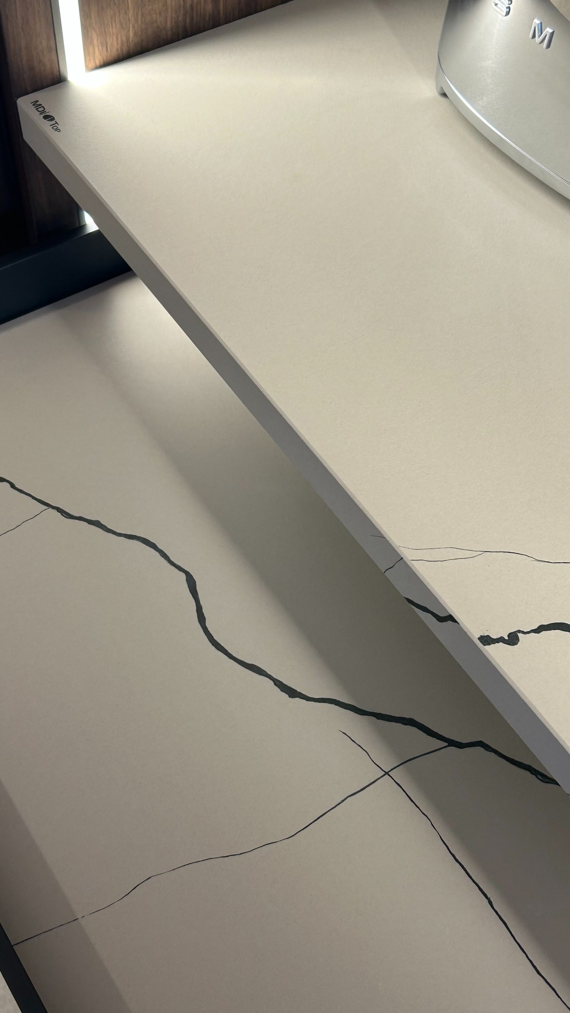 Encimera blanca con vetas oscuras, iluminada desde arriba.