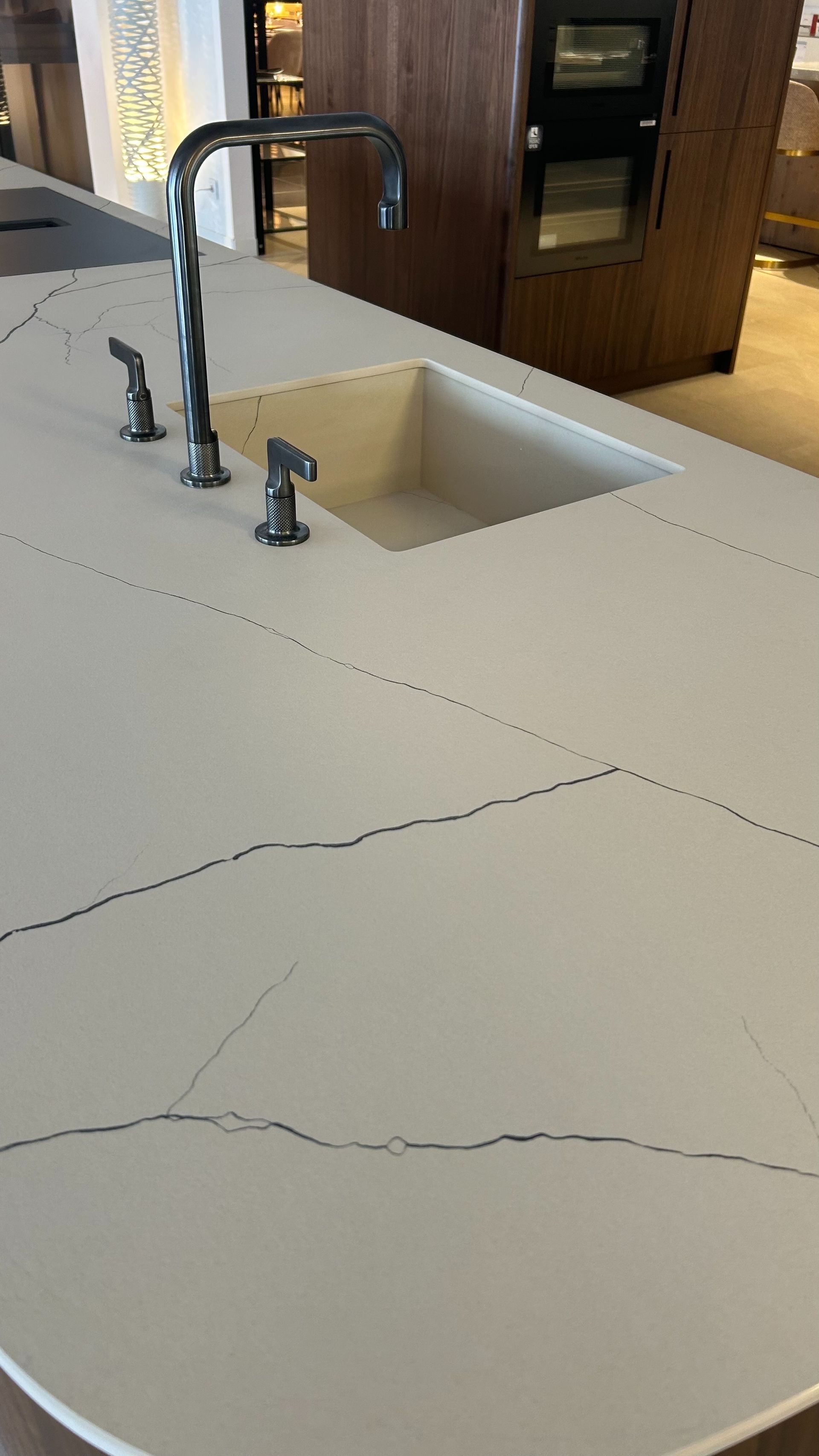 Isla de cocina con encimera blanca, fregadero, grifo y dispensadores de jabón.