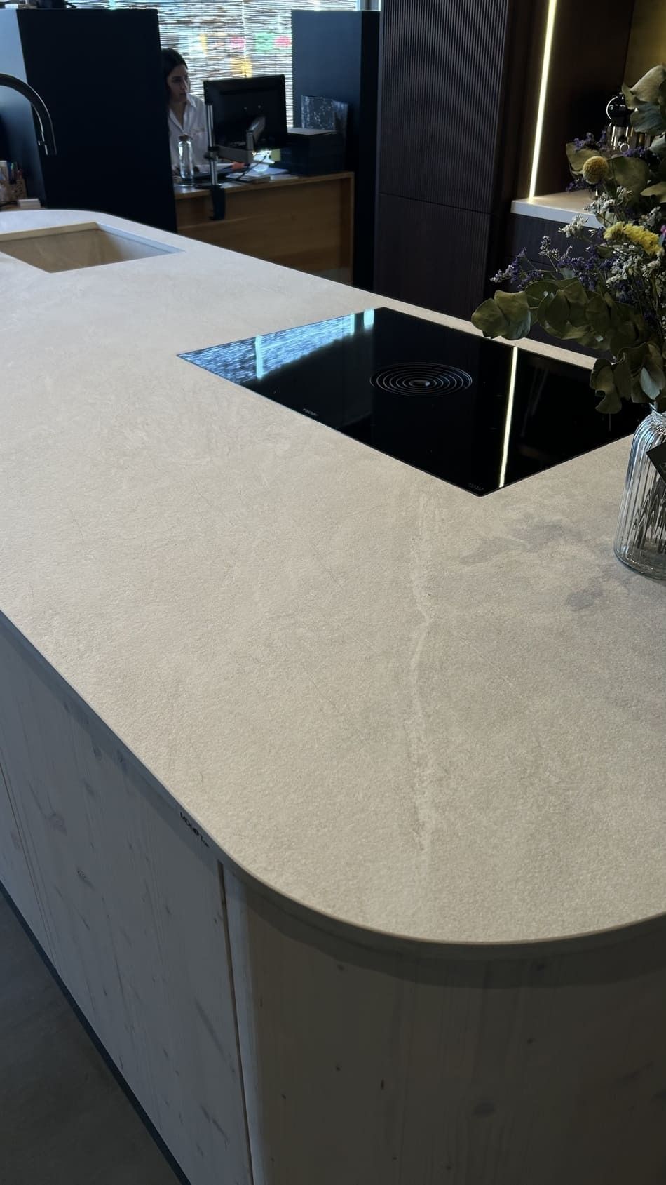 Isla de cocina con estufa negra incorporada y encimeras de color claro.