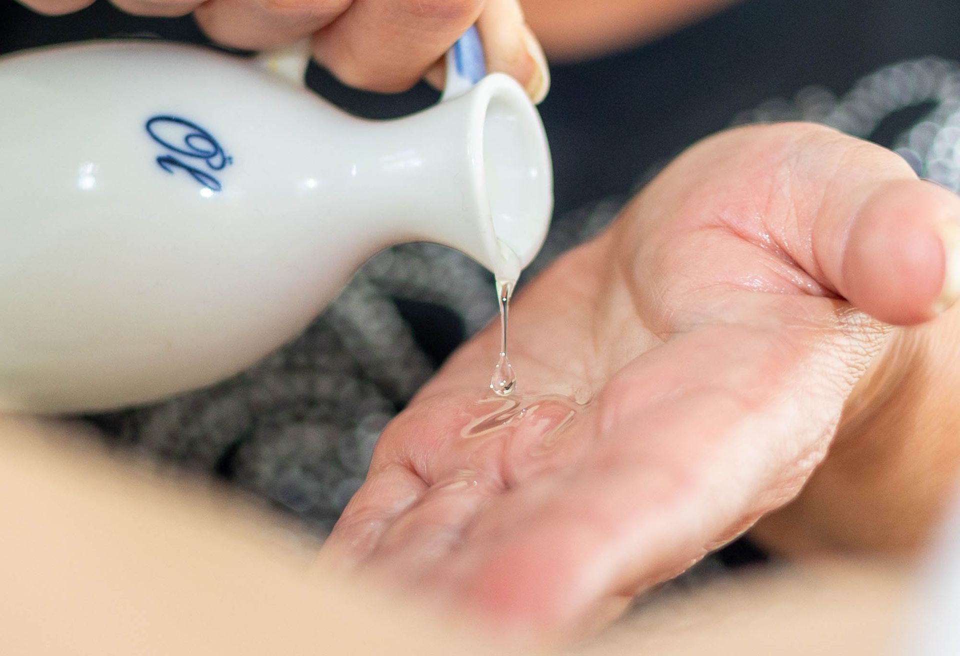 Eine Person gießt einer anderen Person Flüssigkeit in die Hand.