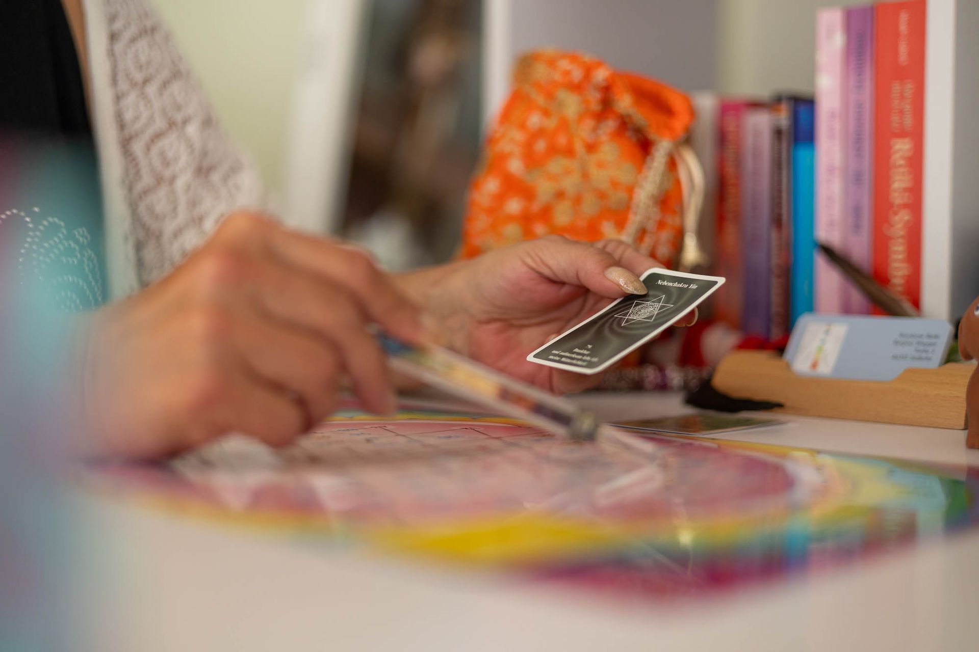 Eine Person sitzt an einem Tisch und hält eine Tarotkarte in der Hand.