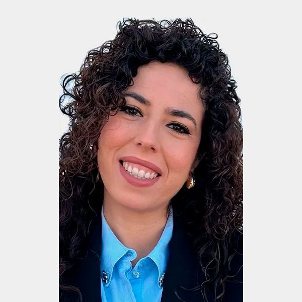 Hombre de ojos marrones, barba y sonriente; viste camisa azul claro y tirantes.