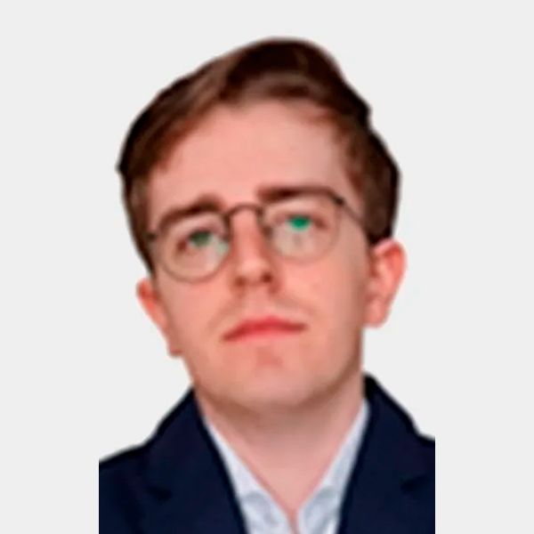 Hombre de ojos marrones, barba y sonriente; viste camisa azul claro y tirantes.