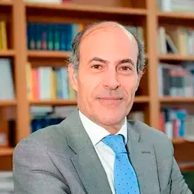 Hombre de ojos marrones, barba y sonriente; viste camisa azul claro y tirantes.