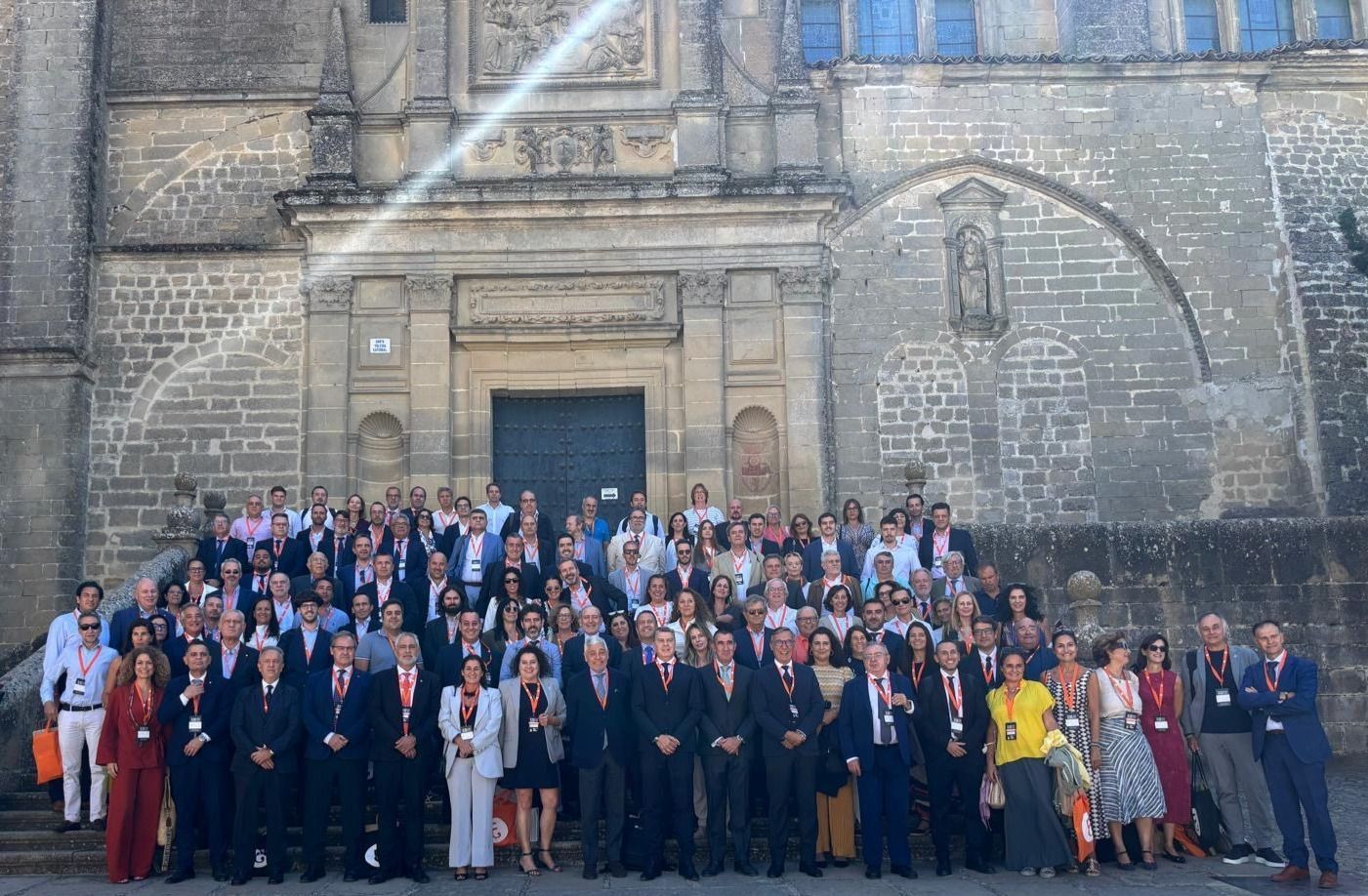 Grupo de personas posando para una foto frente a un edificio de piedra con puertas arqueadas.