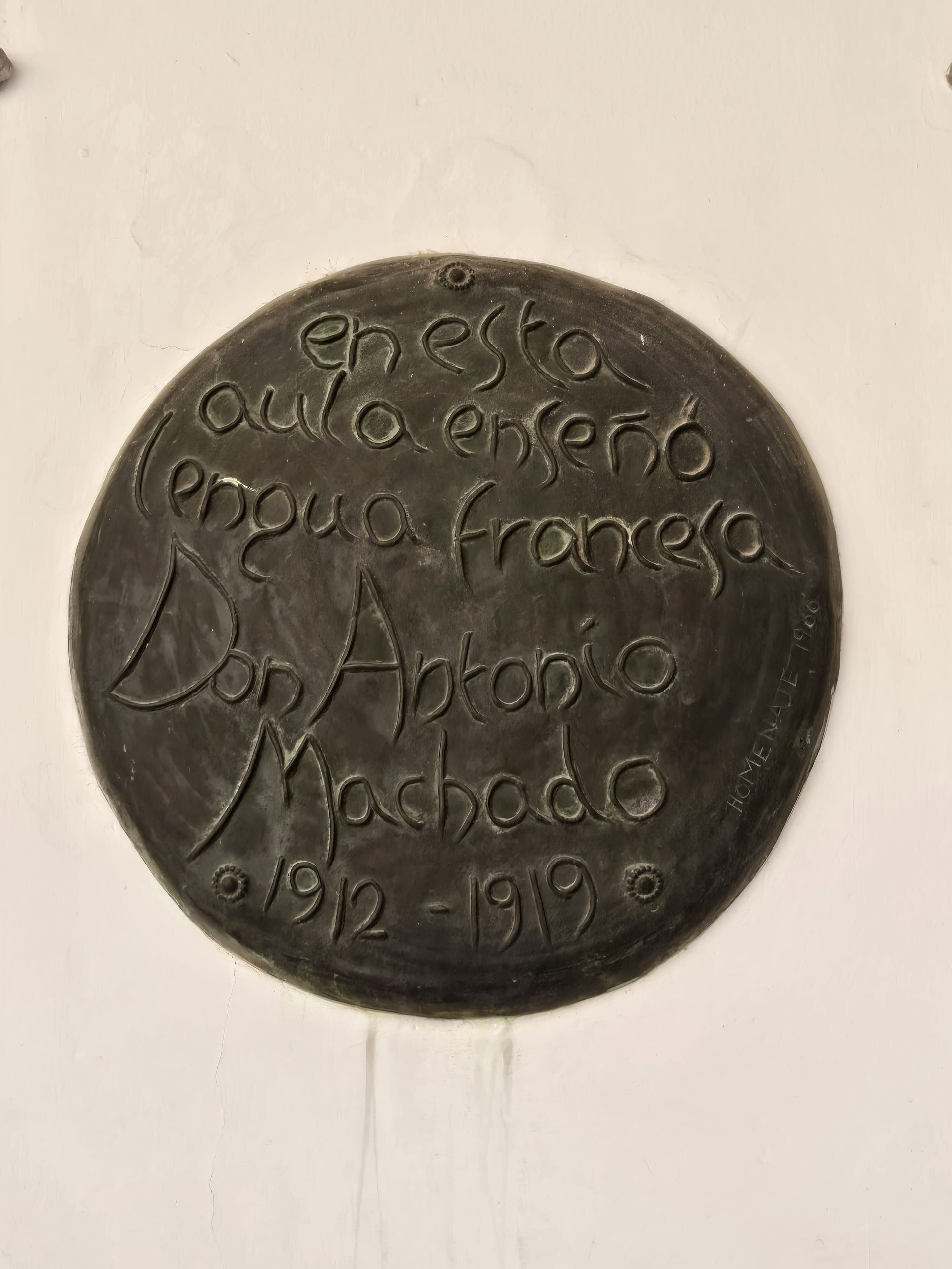 Bronze plaque on white wall: 